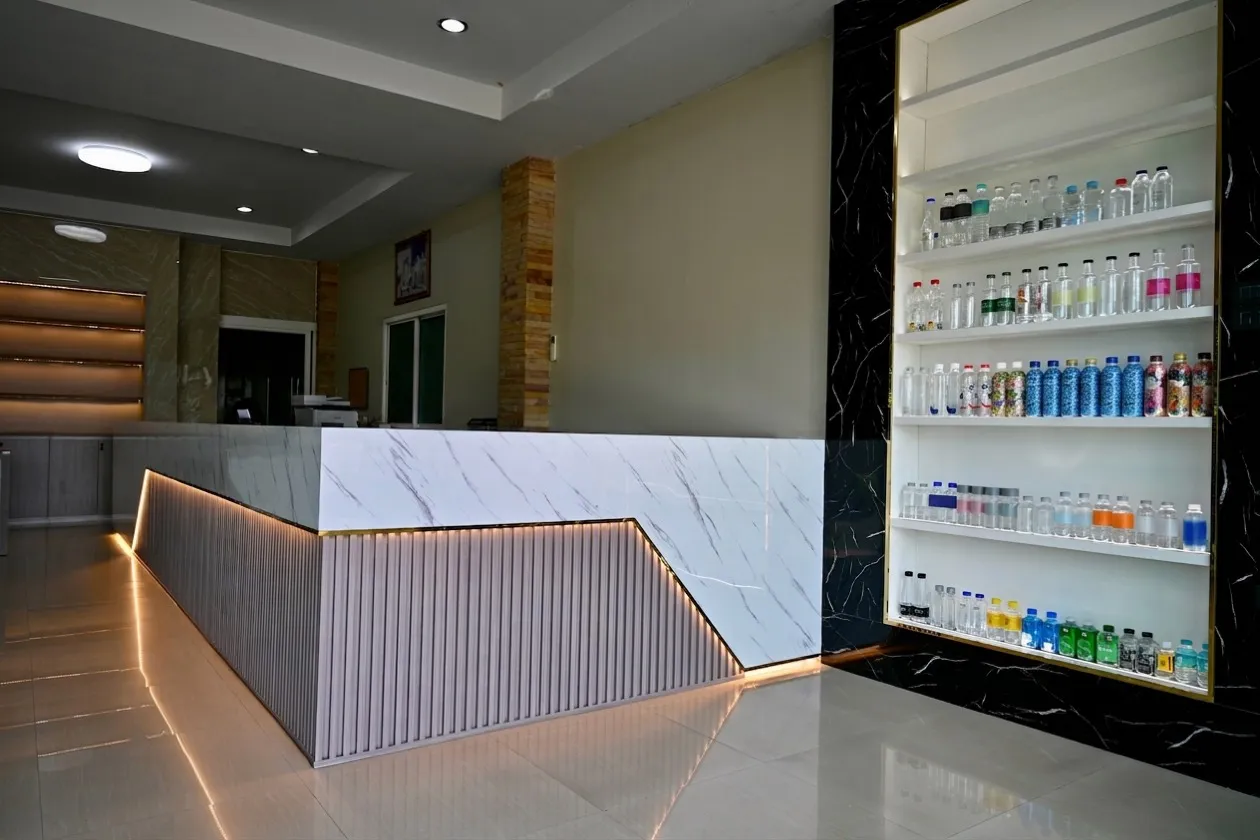 A gold-trimmed display case set into a black marble wall, holding shelves of water bottles in a range of shapes and cap colours.